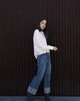 Femme portant un chemisier blanc à col papillon, jeans wide-leg et bottines noires
