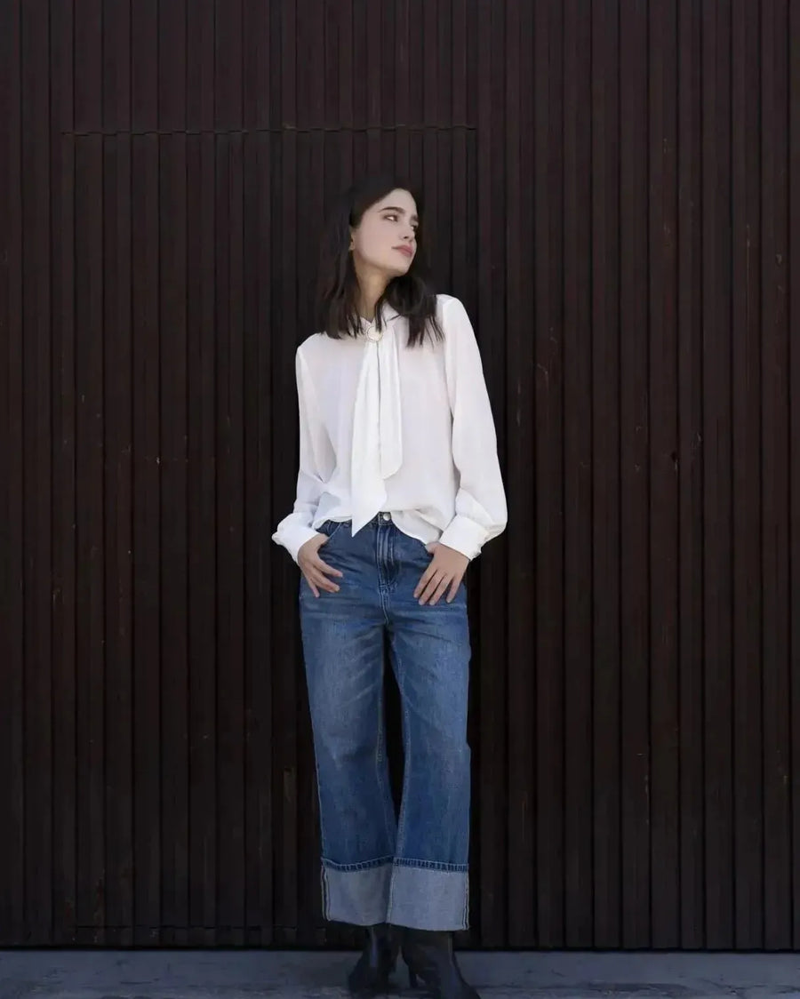 Femme portant un chemisier blanc à col papillon et jeans à jambes larges