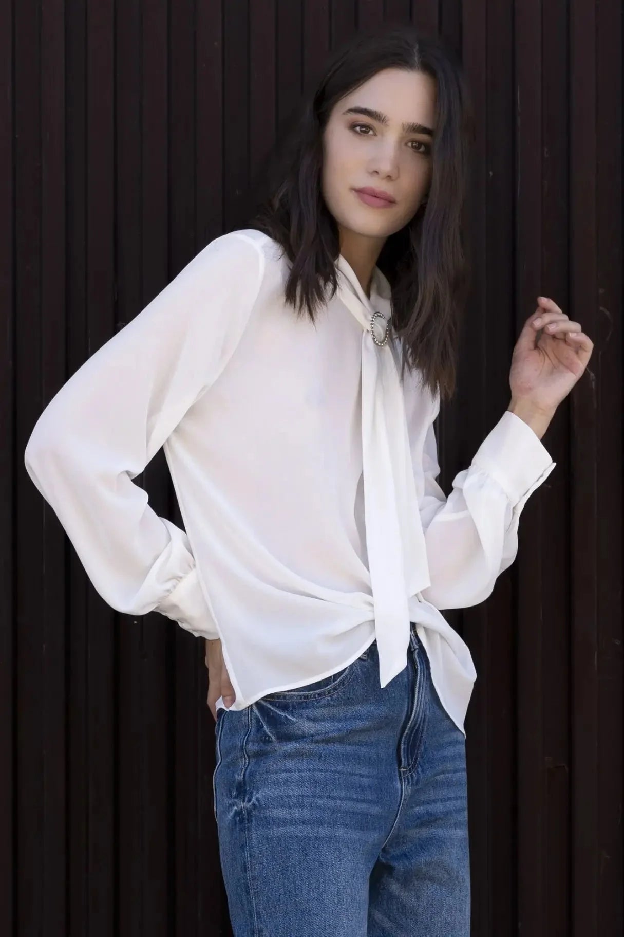 Chemisier blanc à col papillon porté par une femme en jeans et blouse élégante