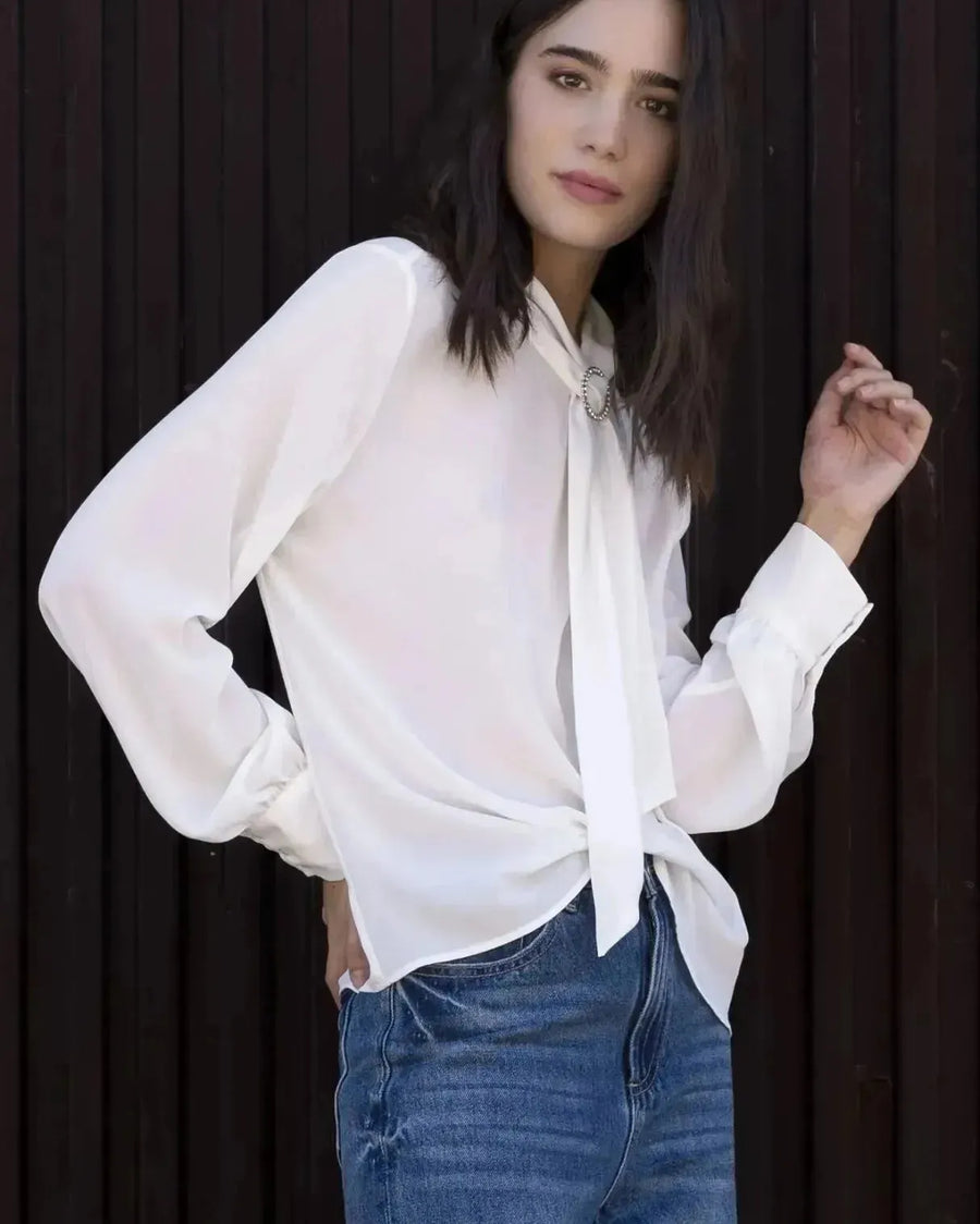 Chemisier blanc à col papillon porté par une femme en jeans et blouse élégante