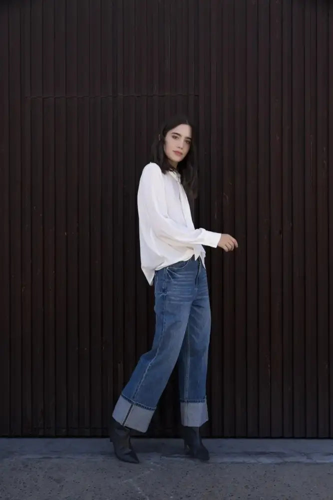 Femme portant un chemisier blanc à col papillon, jeans wide-leg et bottines noires