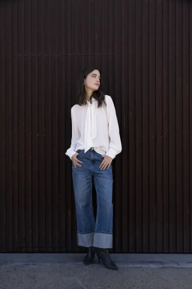 Femme portant un chemisier blanc à col papillon et jeans à jambes larges
