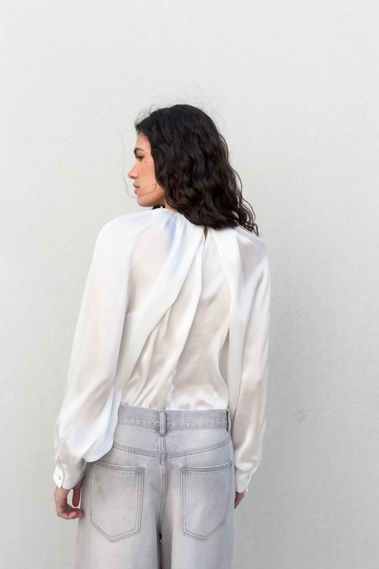 Vue de dos d'une femme en blouse satin élégante, mettant en valeur le design chic et moderne de la blouse satin.