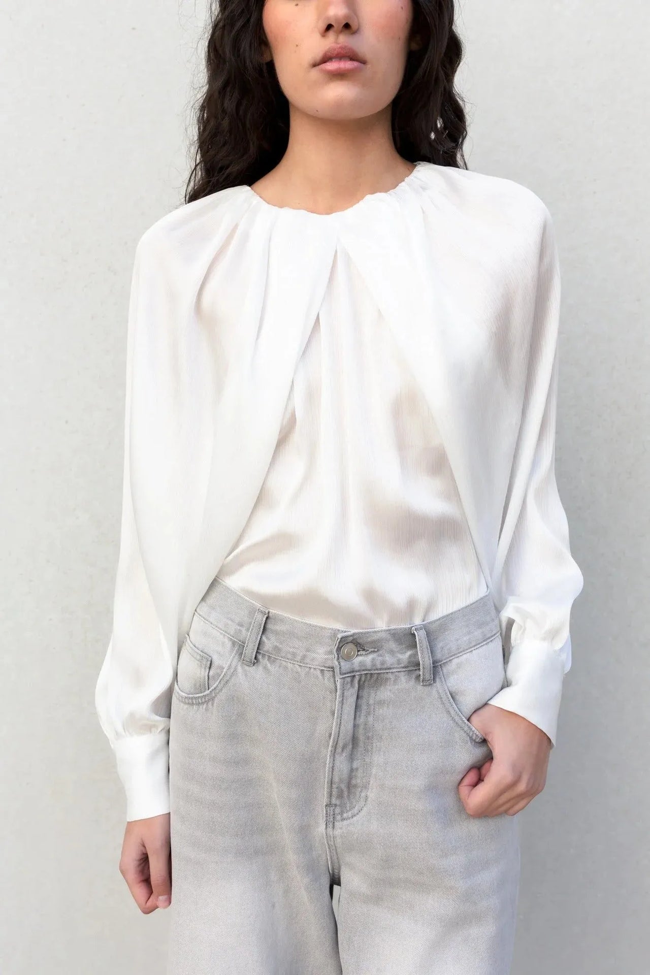 Plan rapproché sur une blouse satin élégante portée par une femme, démontrant le chic et le confort du style.