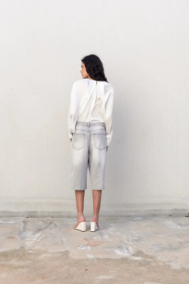 Femme de dos en blouse satin élégante, affichant un look chic et décontracté avec un pantalon en jean.