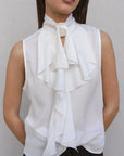 Gros plan sur le chemisier blanc femme avec volants, mettant en évidence le col élégant et raffiné, un choix idéal pour une garde-robe sophistiquée.