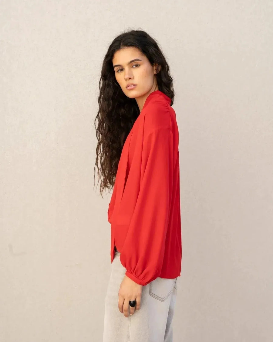 Profil d'un mannequin portant un chemisier col lavallière femme rouge fluide à manches longues, ajoutant une touche moderne à son style.