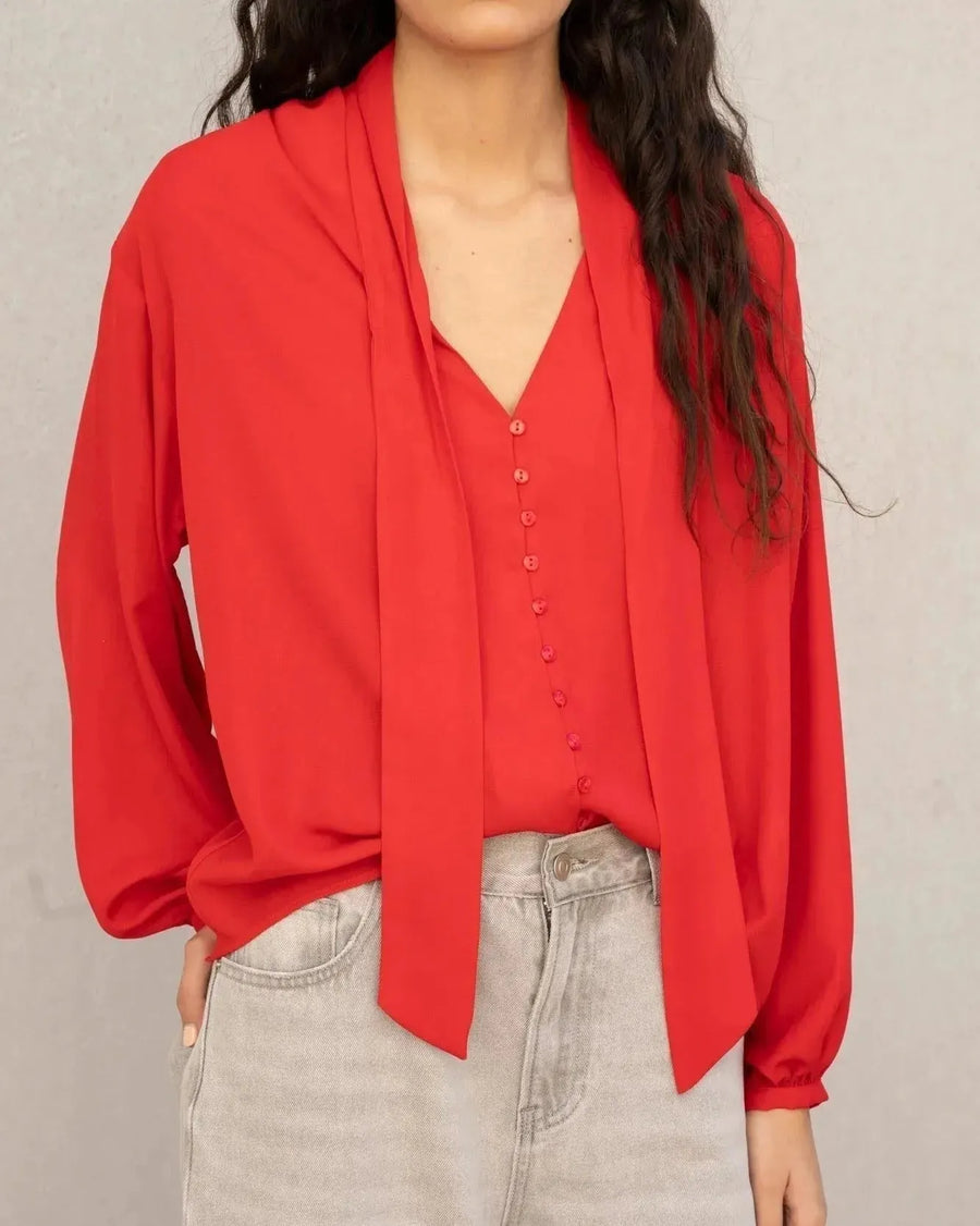 Gros plan sur le chemisier col lavallière femme rouge fluide à manches longues, mettant en valeur les détails et le design chic.