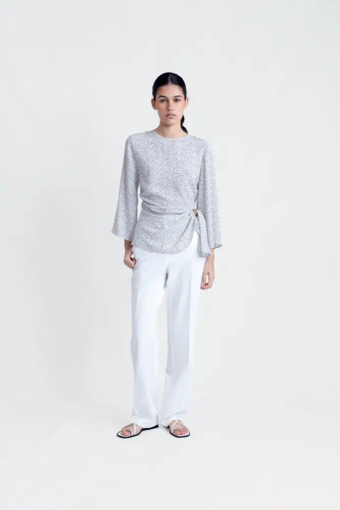 Chemisier femme fluide à pois noirs avec manches larges, associé à un pantalon blanc