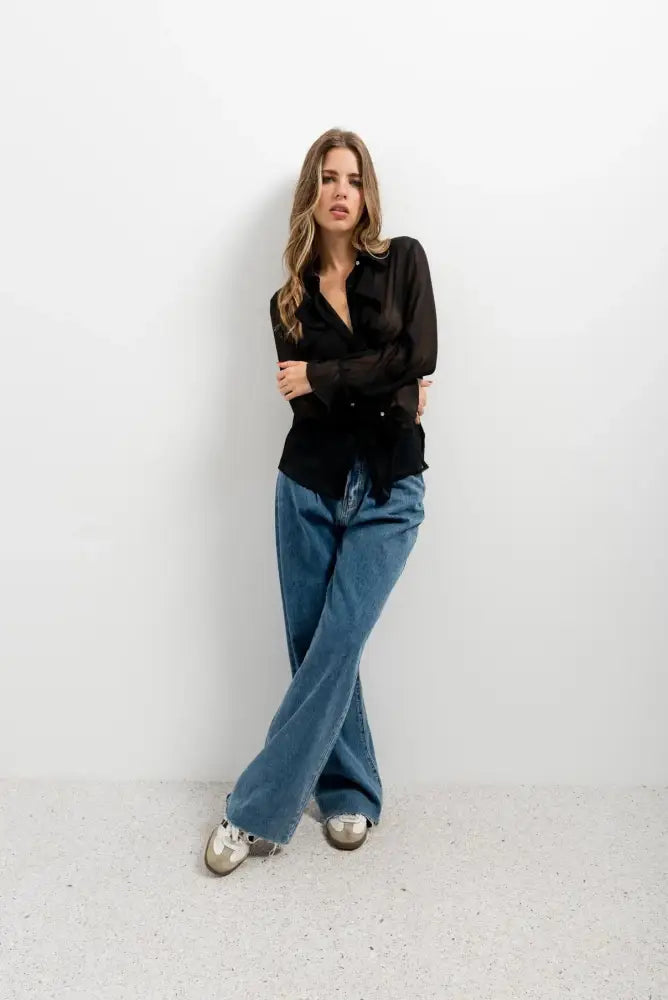 Femme portant chemisier noir transparent avec volants et voile fluide, style chic