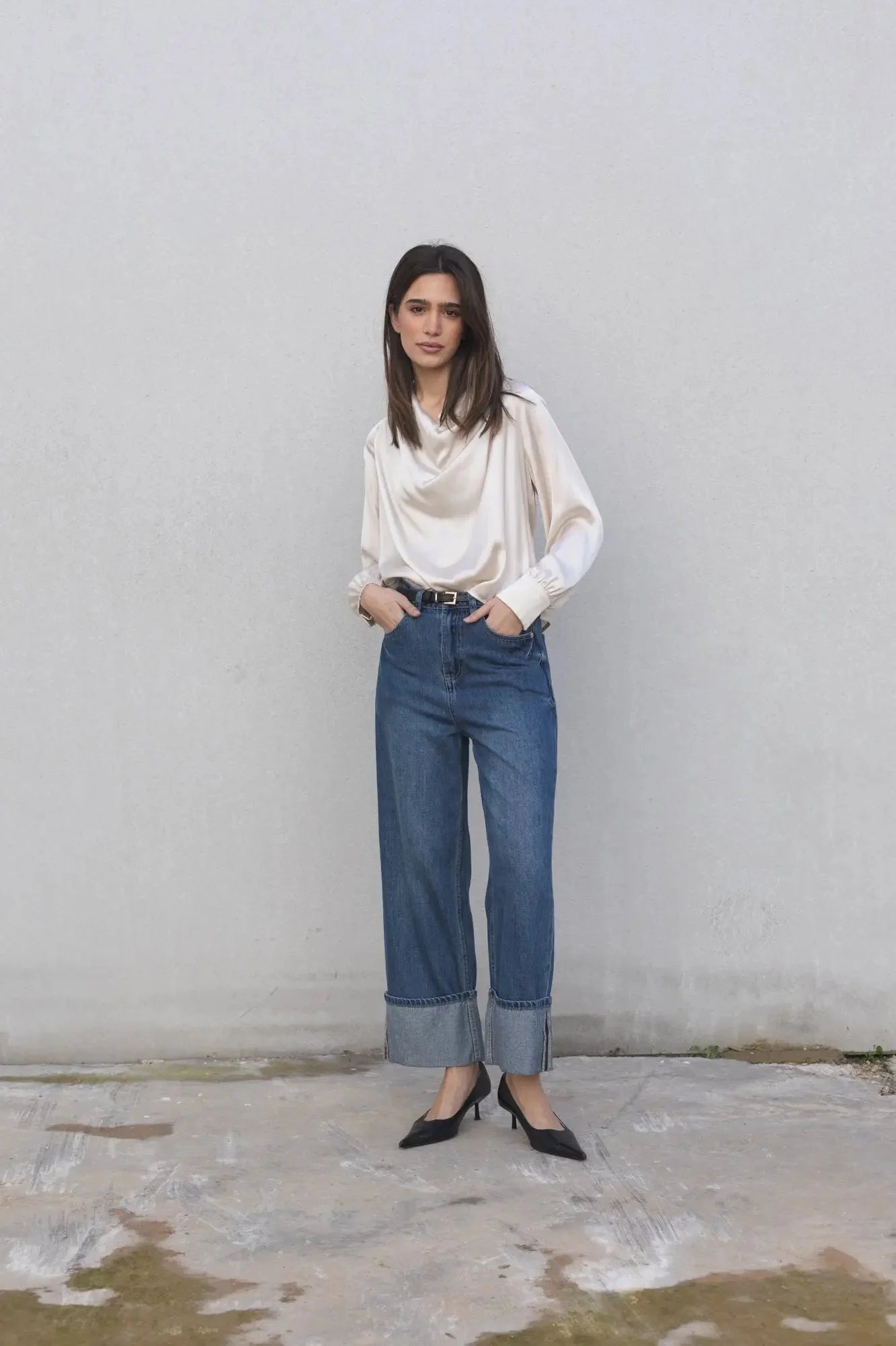 Femme en blouse en satin avec noeud, style chic, jeans foncés et talons noirs