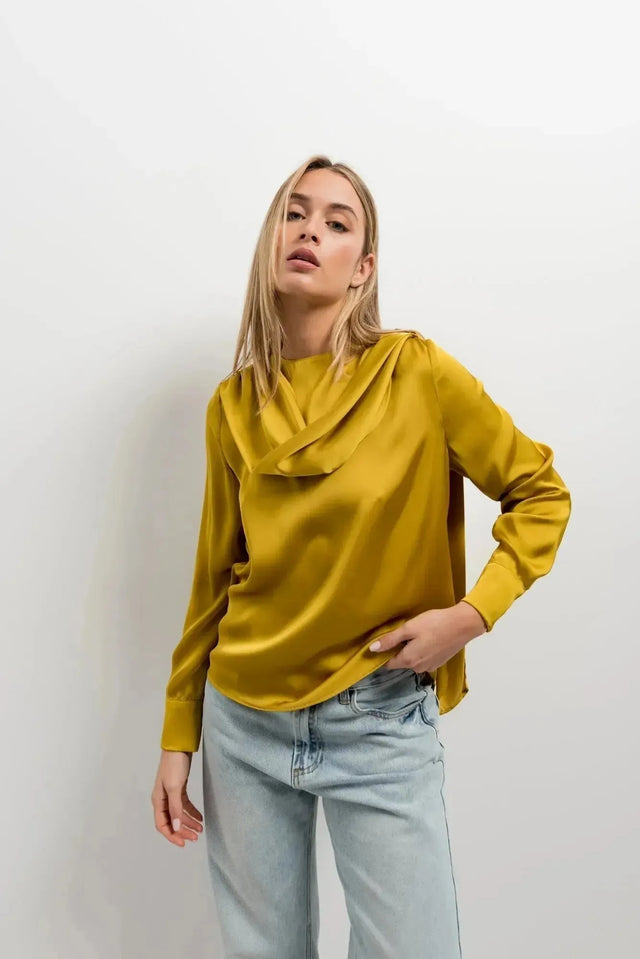 Zoom sur le haut col bénitier satiné jaune moutarde avec plis élégants, mettant en valeur le style chic de la model.