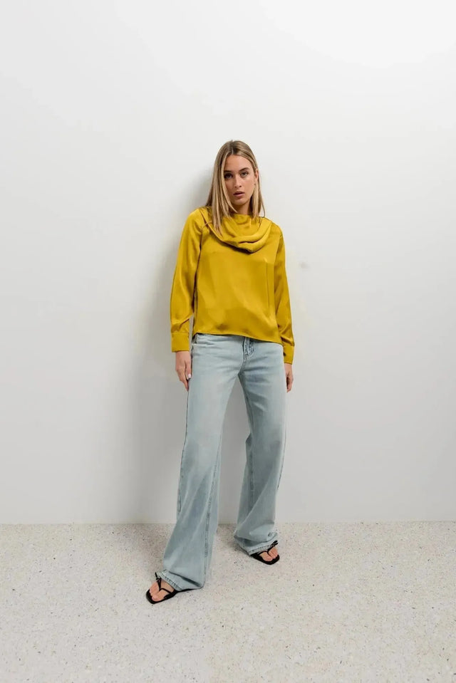 Haut col bénitier satiné jaune moutarde avec plis élégants pour un look chic, porté par une femme avec un fond neutre.