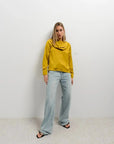 Haut col bénitier satiné jaune moutarde avec plis élégants pour un look chic, porté par une femme avec un fond neutre.