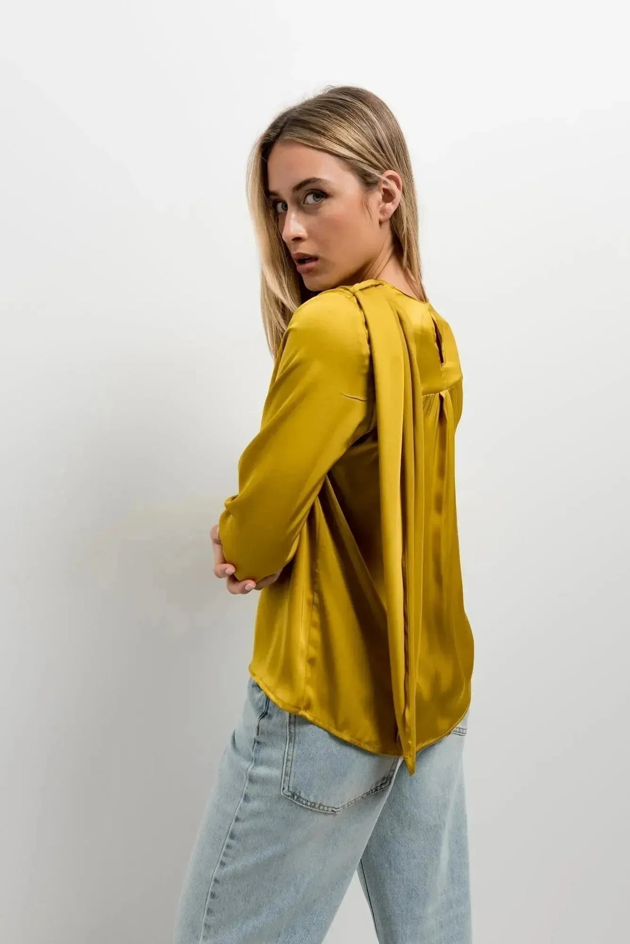 Vue arrière du haut col bénitier satiné jaune moutarde avec plis élégants, montrant le détail du design sur une femme.