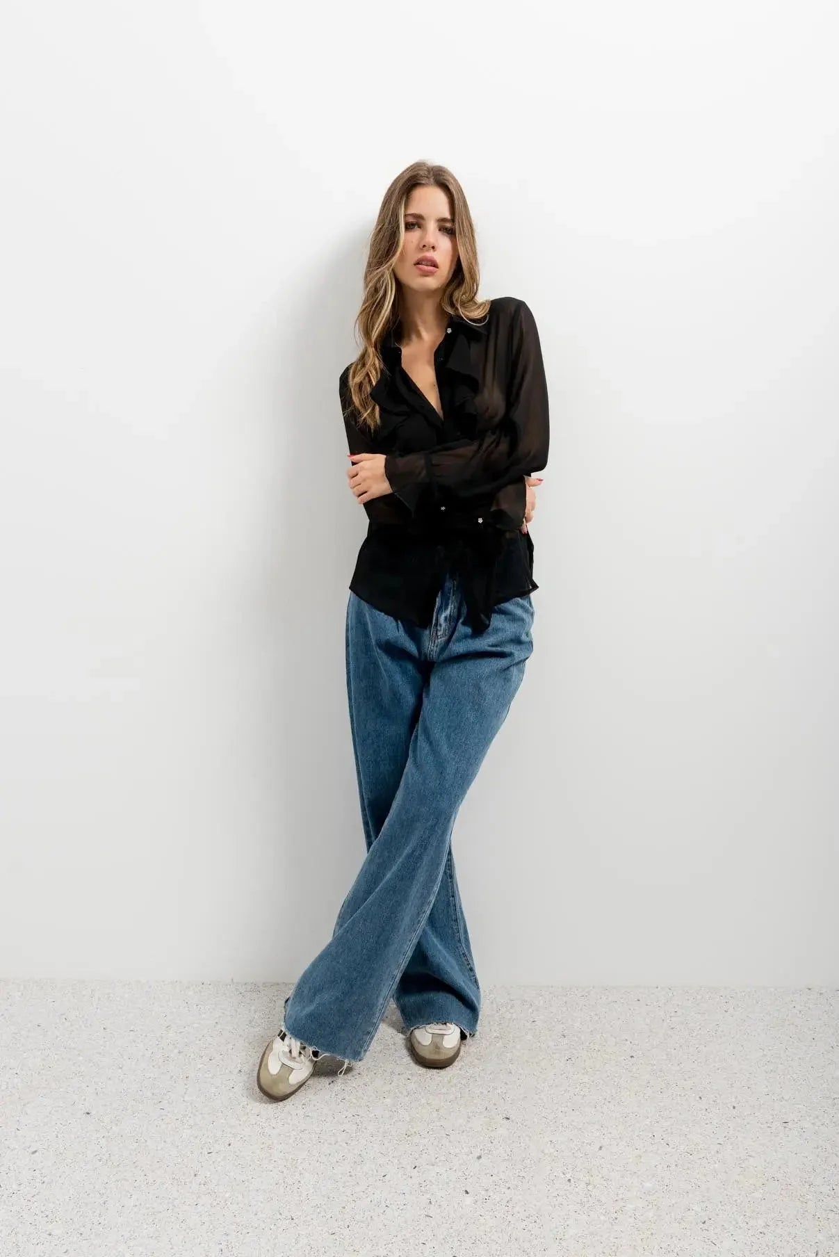 Femme portant chemisier noir transparent avec volants et voile fluide, style chic
