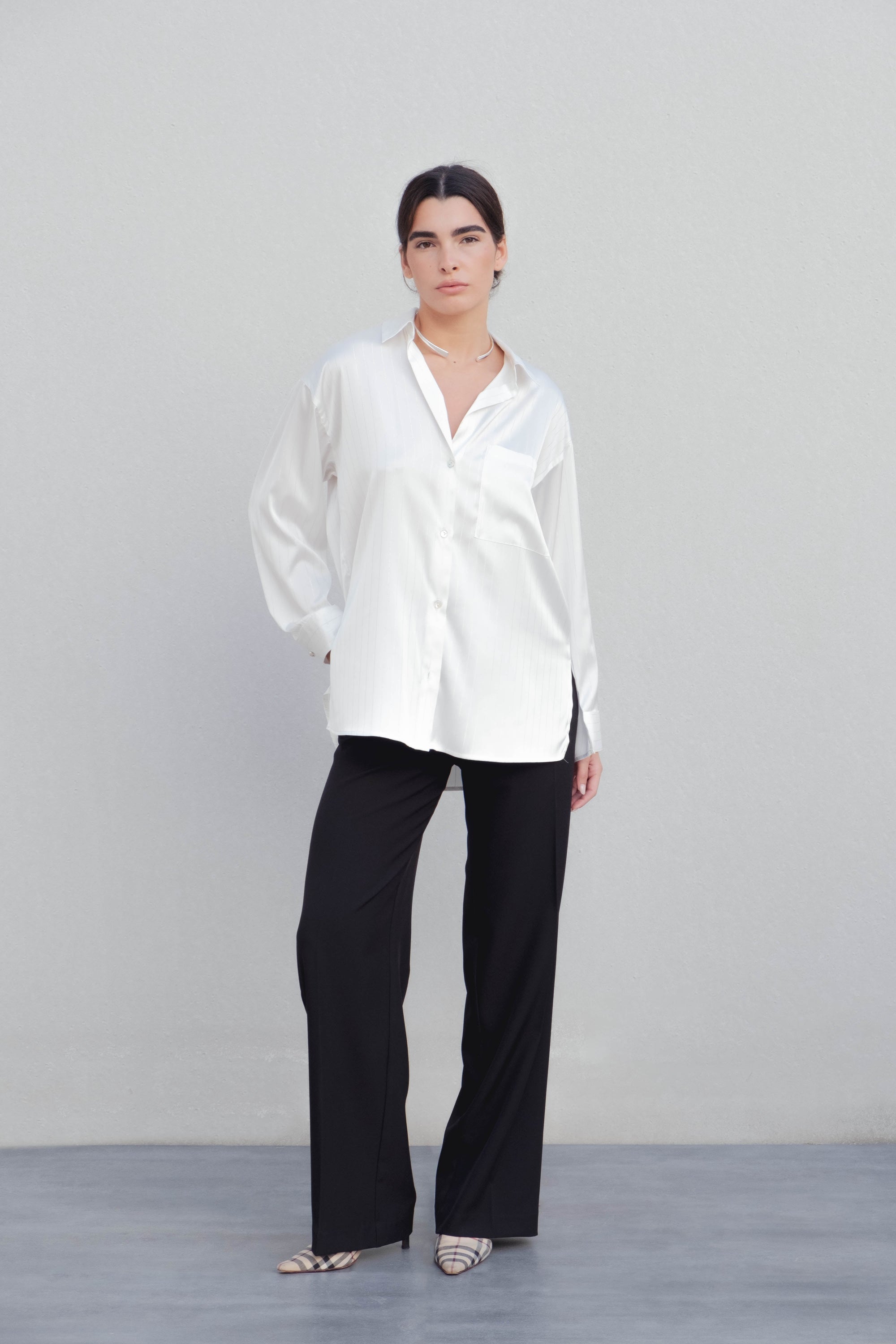Chemise à rayures fines blanche crème, chemisier rayure femme, associée à un pantalon noir pour un style professionnel.