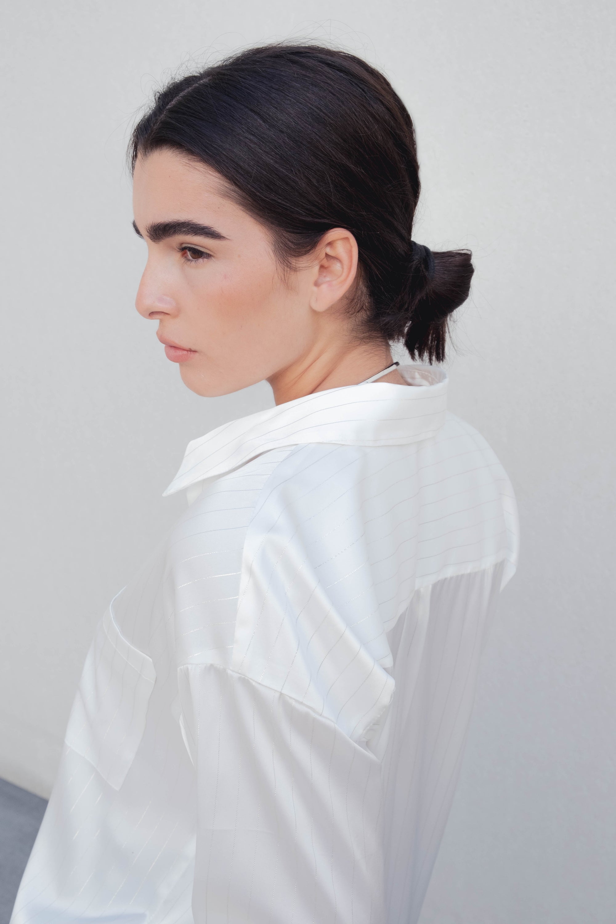 Vue de profil de la chemise à rayures fines blanche crème, mettant en avant le col à revers et le style du chemisier rayure femme.