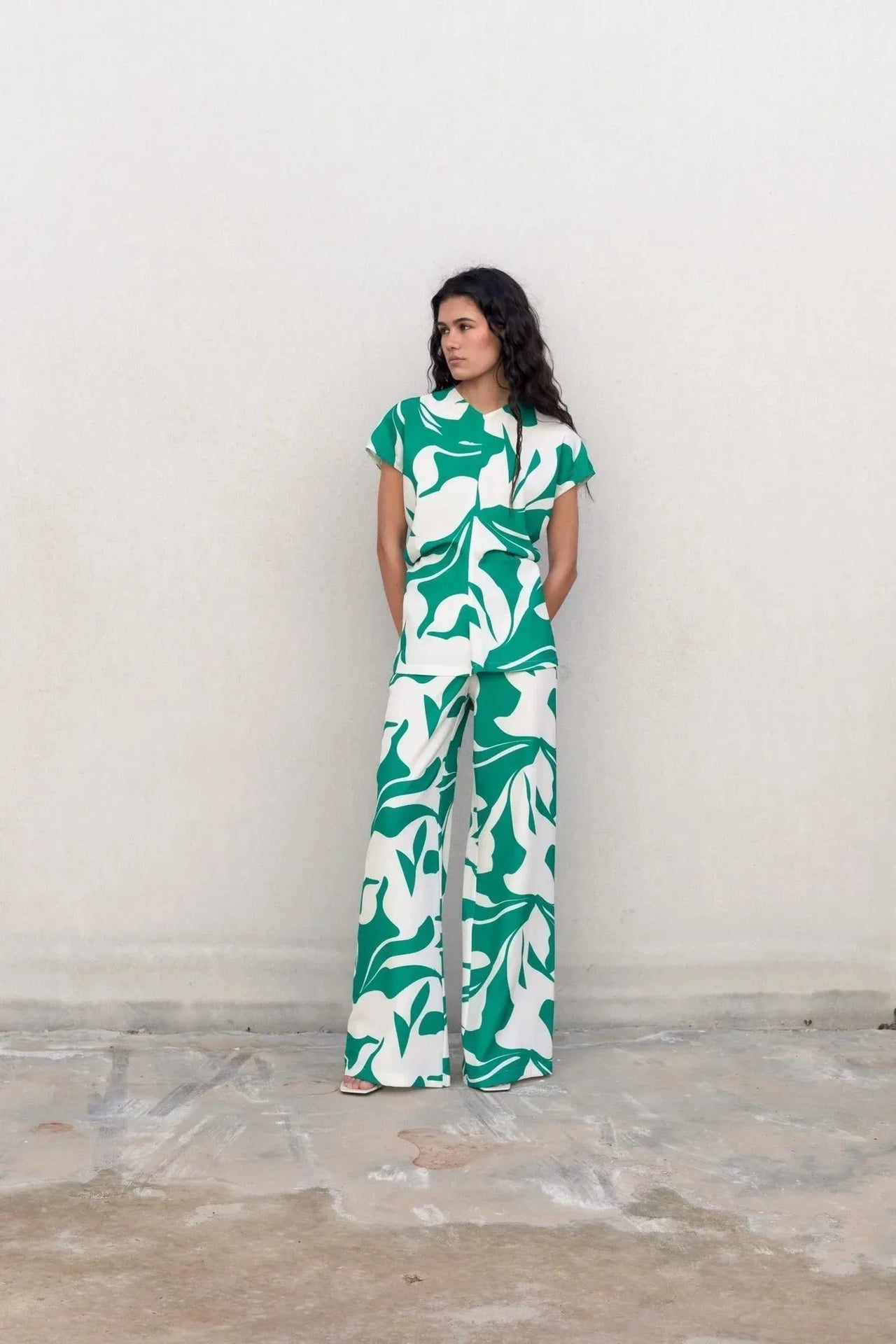 Modèle portant un haut fluide femme chic imprimé froncés avec jambe large, affichant un look élégant sur fond neutre.