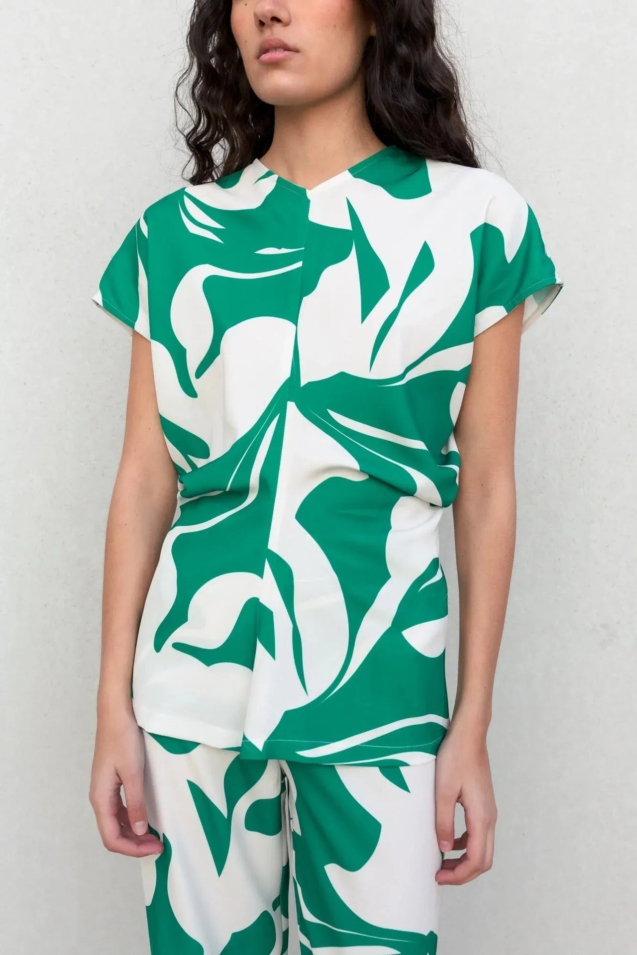 Gros plan sur un haut fluide femme chic imprimé froncés avec jambe large, mettant en avant la texture et le motif coloré.