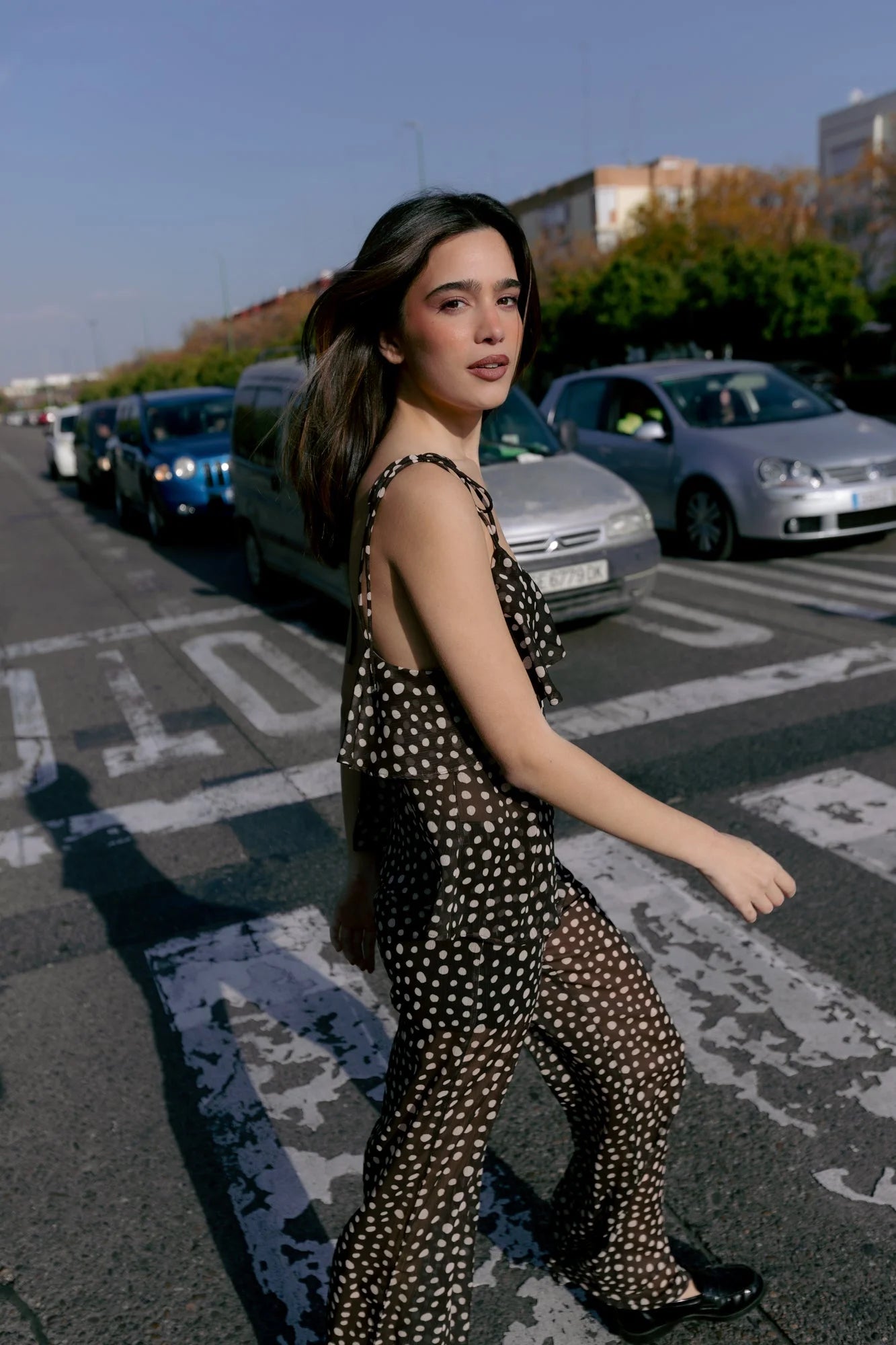 Femme portant une combinaison fluide à pois blancs et volants, style élégant et chic