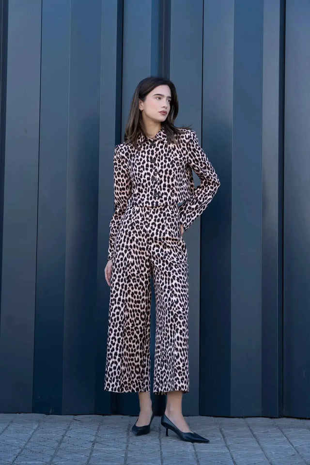 Femme élégante en veste blazer leopard femme, style unique avec imprimé animal, se tenant devant un mur pour une allure chic.