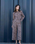 Femme élégante en veste blazer leopard femme, style unique avec imprimé animal, se tenant devant un mur pour une allure chic.