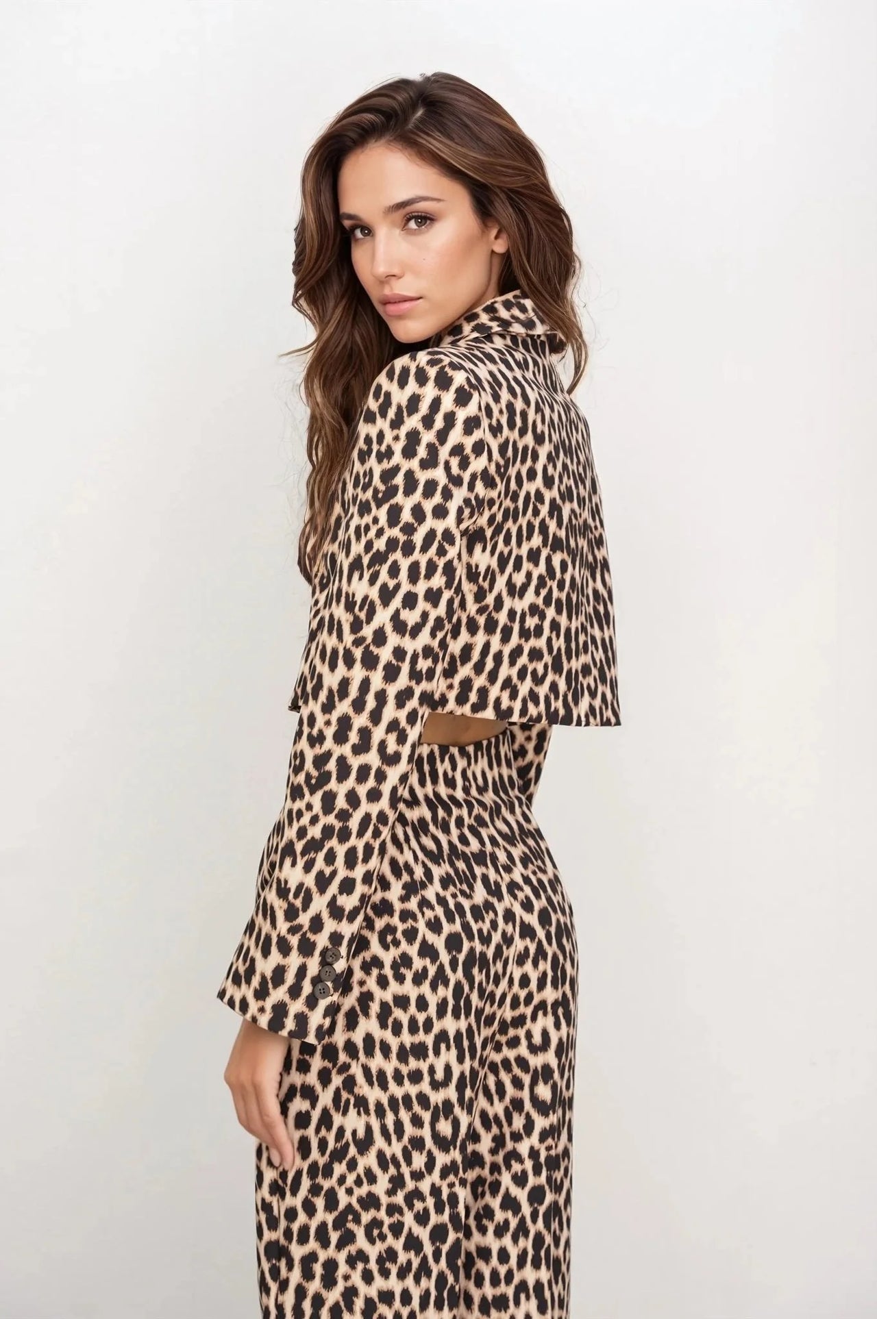 Femme de profil en veste blazer leopard femme, style unique avec imprimé animal, devant un fond minimaliste.