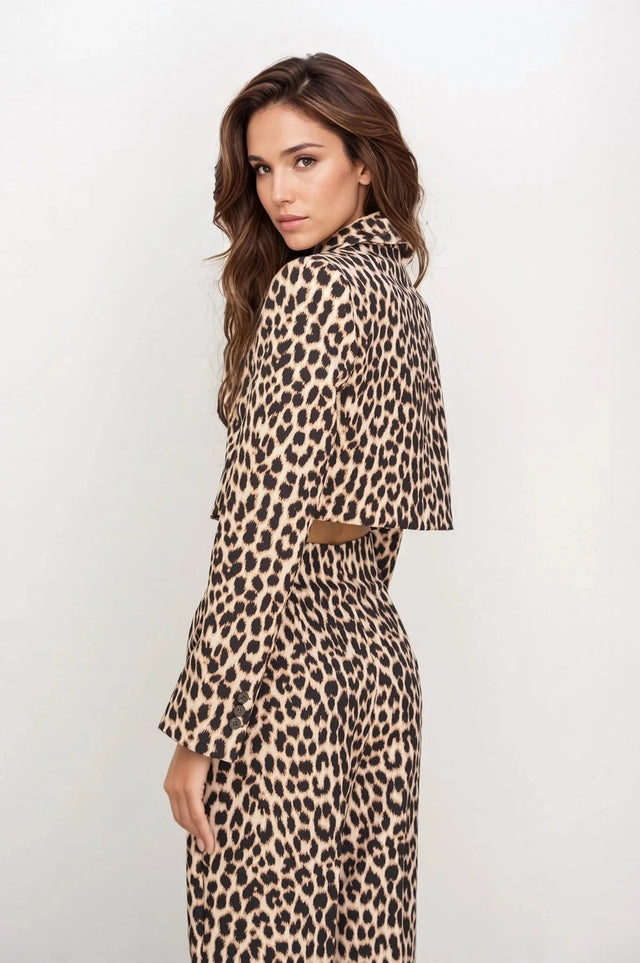 Femme de profil en veste blazer leopard femme, style unique avec imprimé animal, devant un fond minimaliste.