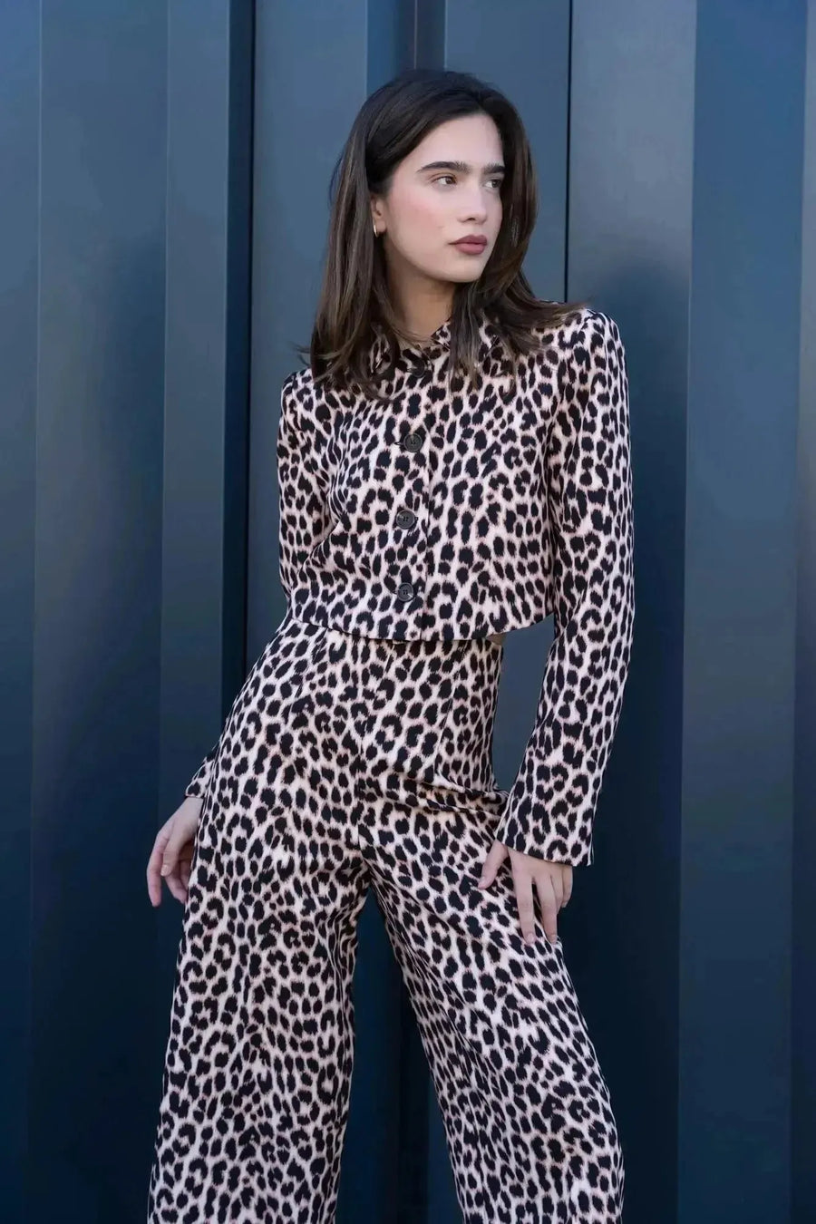 Modèle portant une veste blazer leopard femme, style unique avec imprimé animal, pose devant un mur moderne.