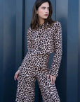 Modèle portant une veste blazer leopard femme, style unique avec imprimé animal, pose devant un mur moderne.