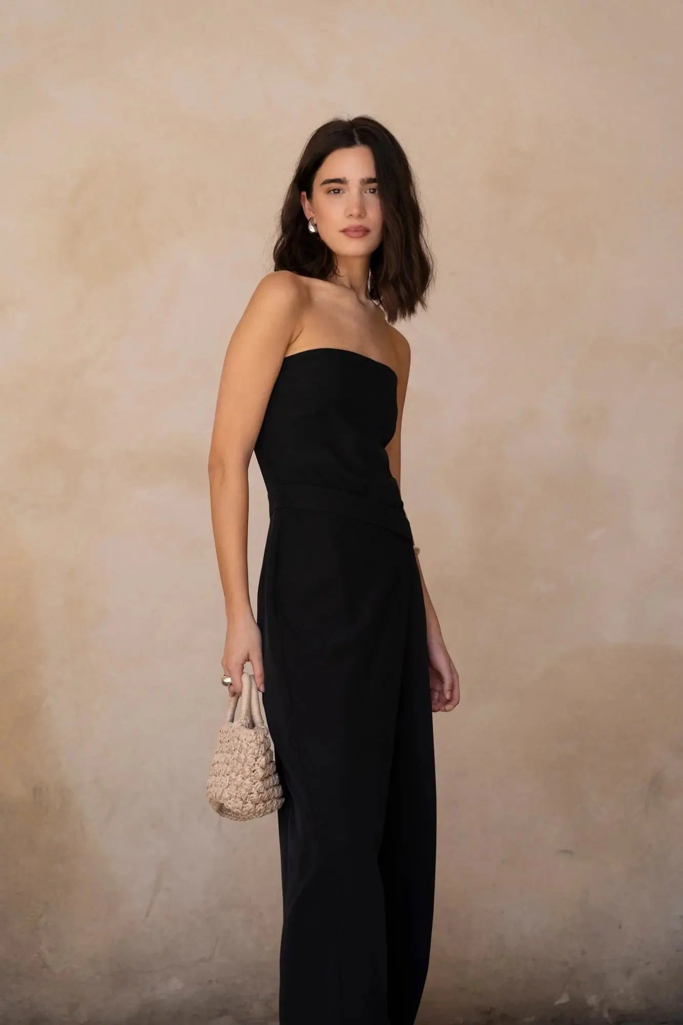 Modèle posant avec une combinaison bustier noir élégante à pantalon fluide, tenue parfaite pour des événements chics.