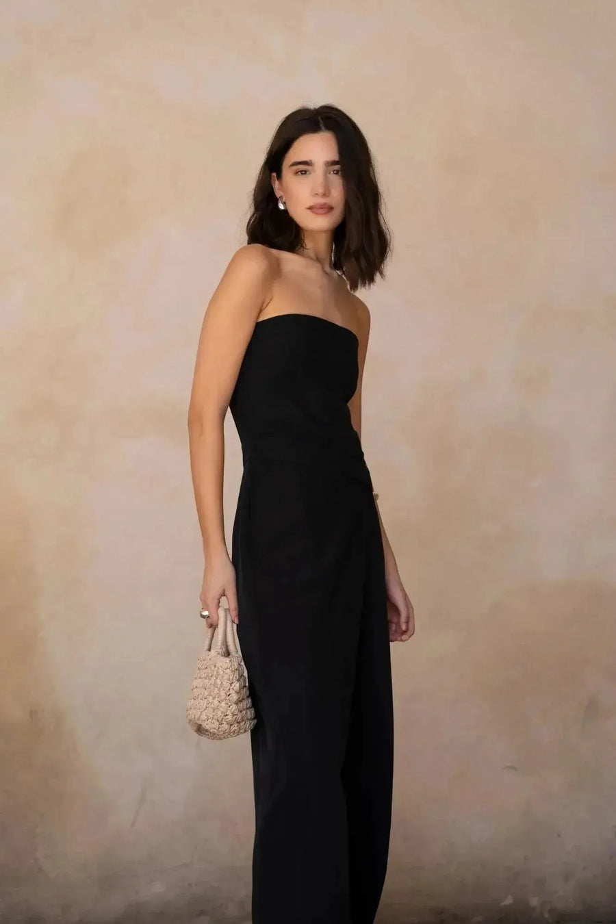 Modèle posant avec une combinaison bustier noir élégante à pantalon fluide, tenue parfaite pour des événements chics.