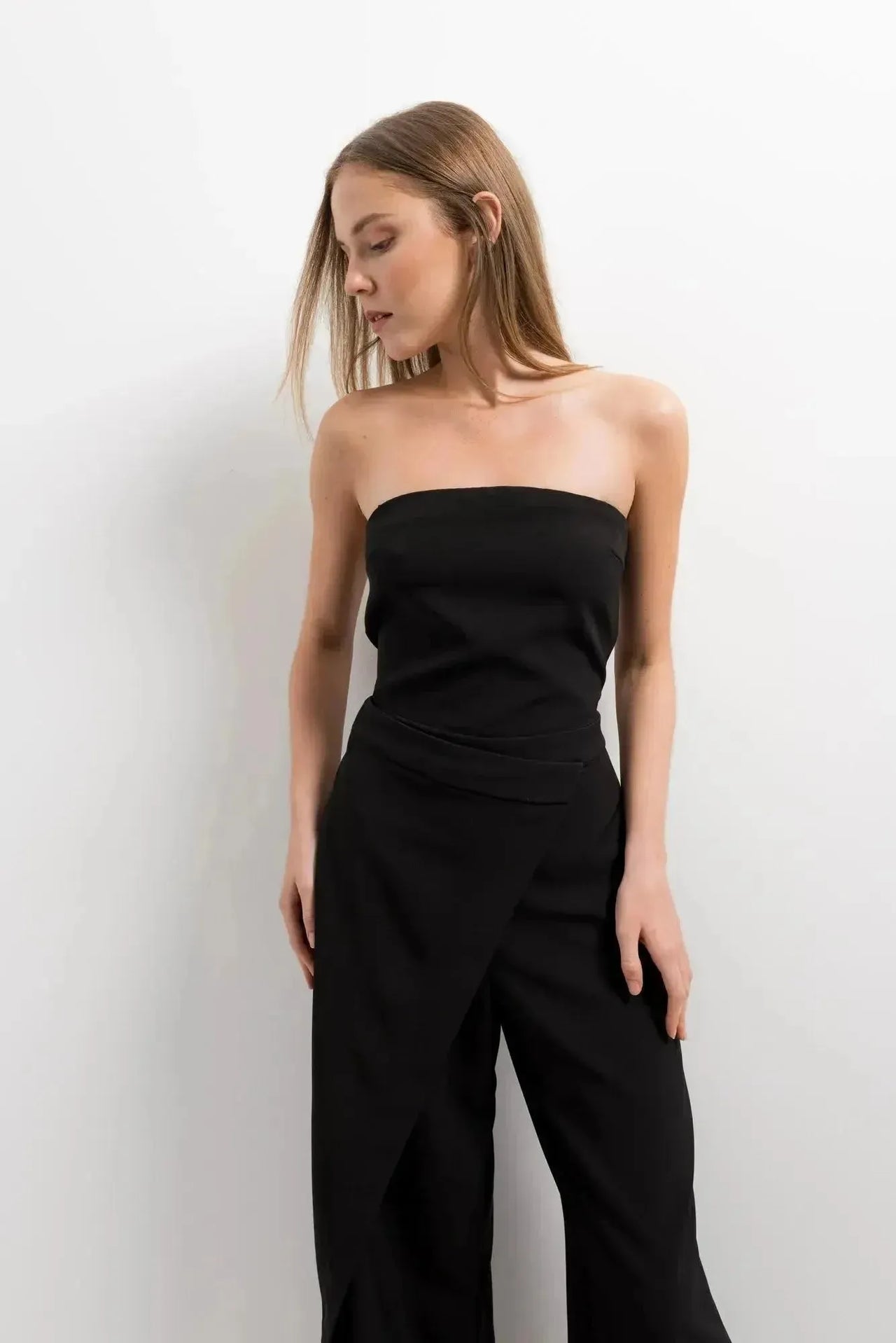 Vue rapprochée d'une combinaison bustier noir élégante à pantalon fluide, avec détail wrap, idéale pour des occasions spéciales.