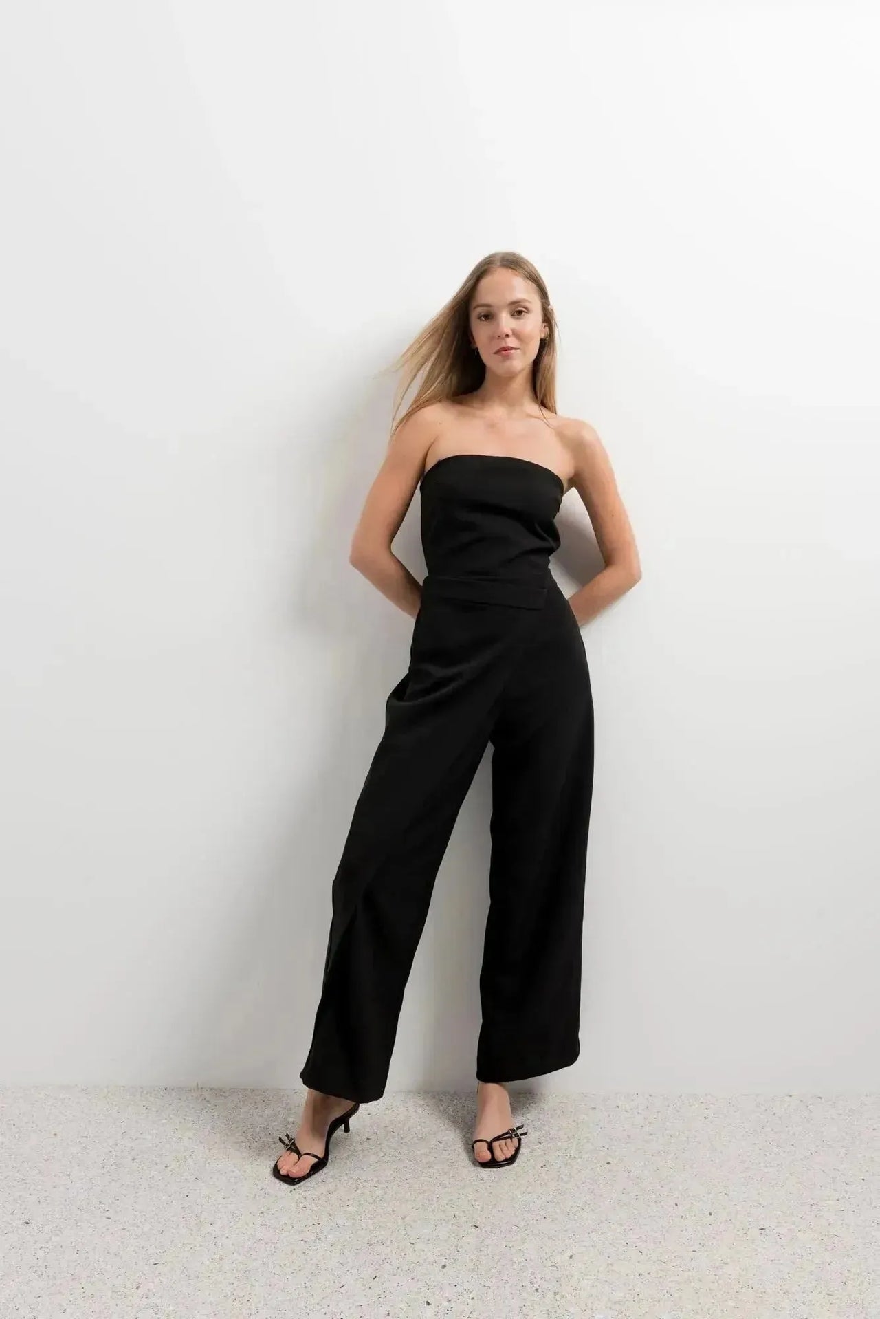 Modèle portant une combinaison bustier noir élégante à pantalon fluide, mettant en valeur un style chic et audacieux.