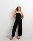 Modèle portant une combinaison bustier noir élégante à pantalon fluide, mettant en valeur un style chic et audacieux.