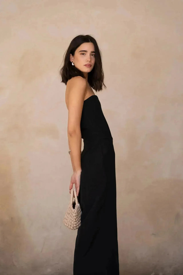 Femme avec combinaison bustier noir élégante à pantalon fluide, ajoutant une touche d'originalité à son look.