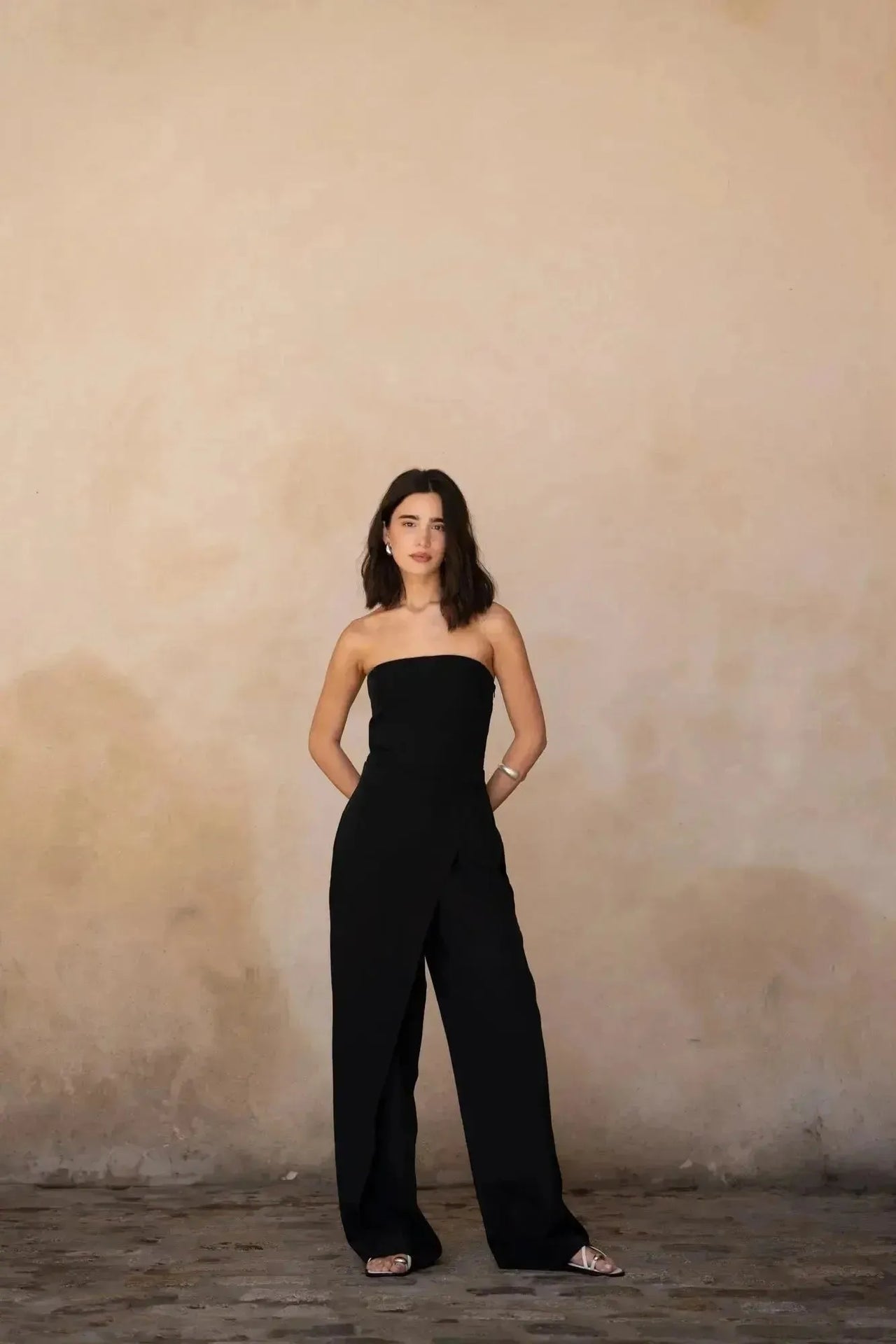 Modèle déambulant avec une combinaison bustier noir élégante à pantalon fluide, capturant un style contemporain.