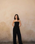 Modèle déambulant avec une combinaison bustier noir élégante à pantalon fluide, capturant un style contemporain.