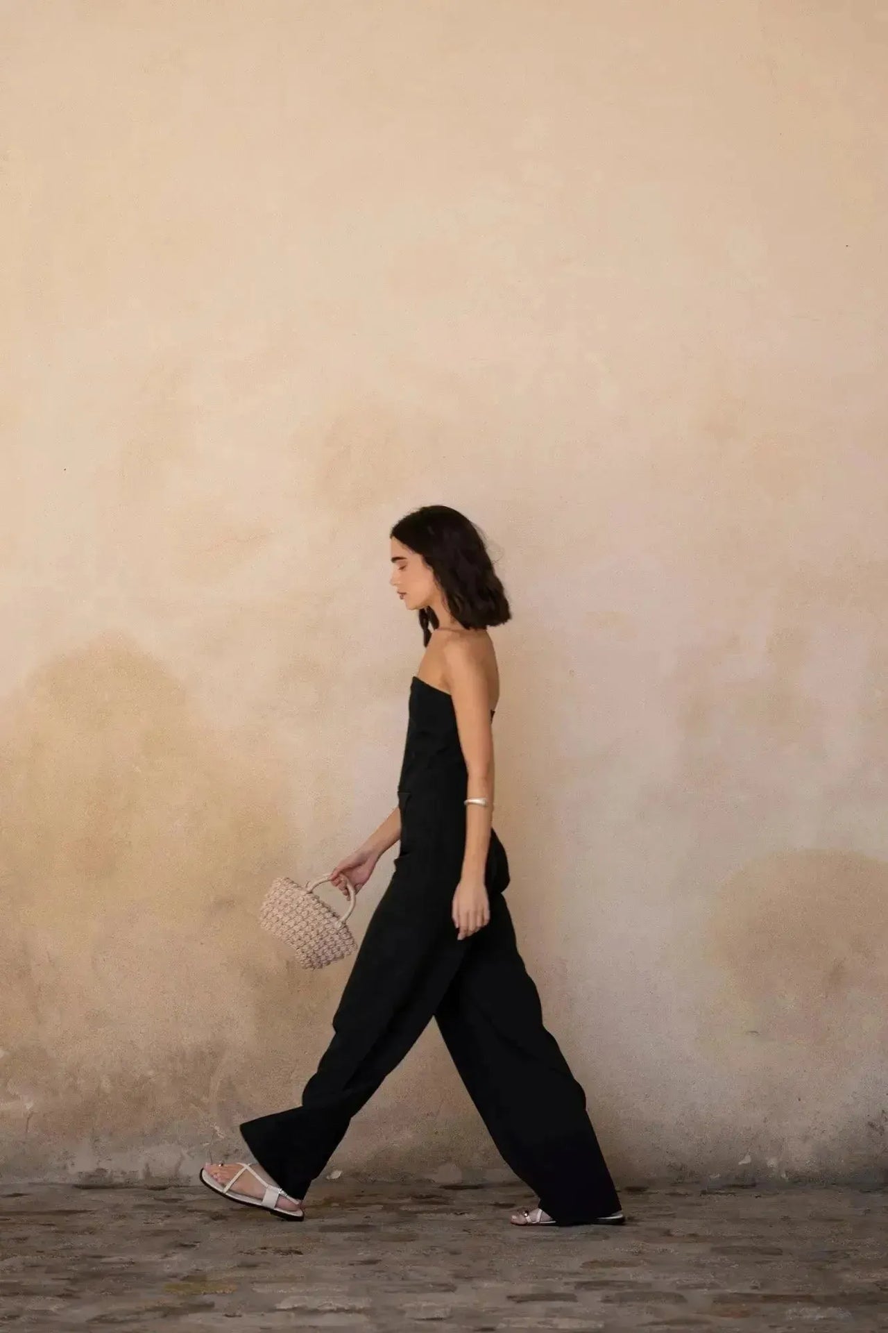 Femme élégante en combinaison bustier noir à pantalon fluide, parfaite pour une sortie ou un cocktail.