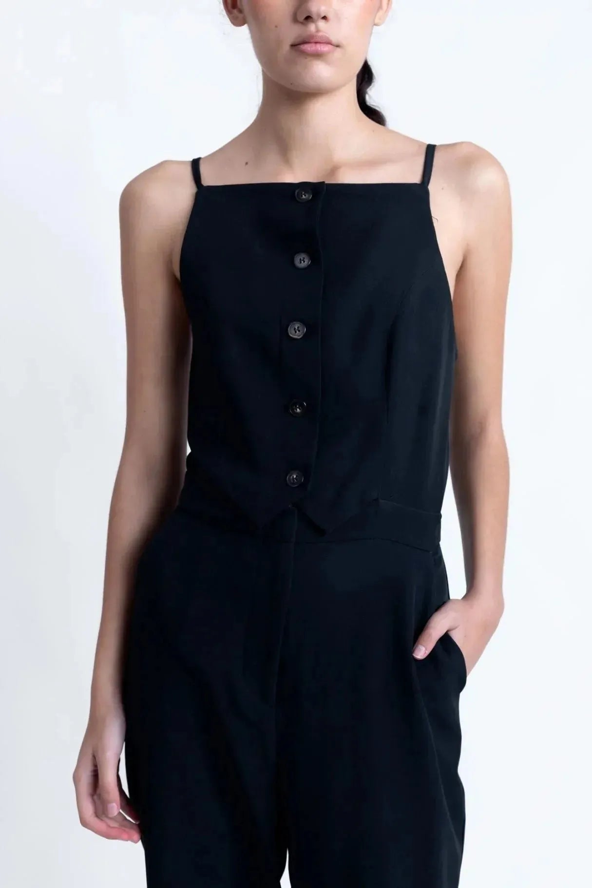 Zoom sur la combinaison noire élégante à boutons, mettant en avant le détail des boutons et le tissu fluide, idéale pour un style minimaliste.