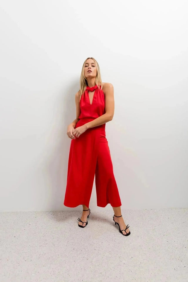 Femme en pose avec un pantalon jupe femme rouge éclatant taille haute, ajoutant une touche chic à son look pour une soirée.
