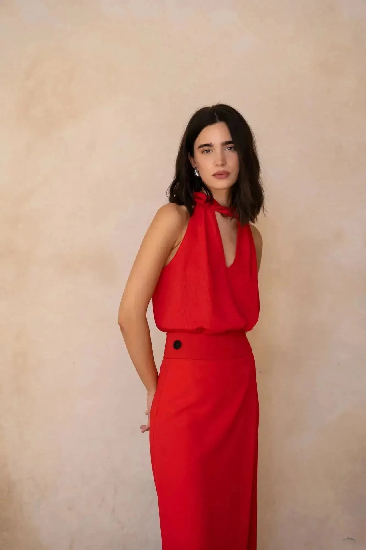 Modèle portant un pantalon jupe femme rouge éclatant taille haute, en tissu fluide, parfaitement adapté pour une soirée élégante.