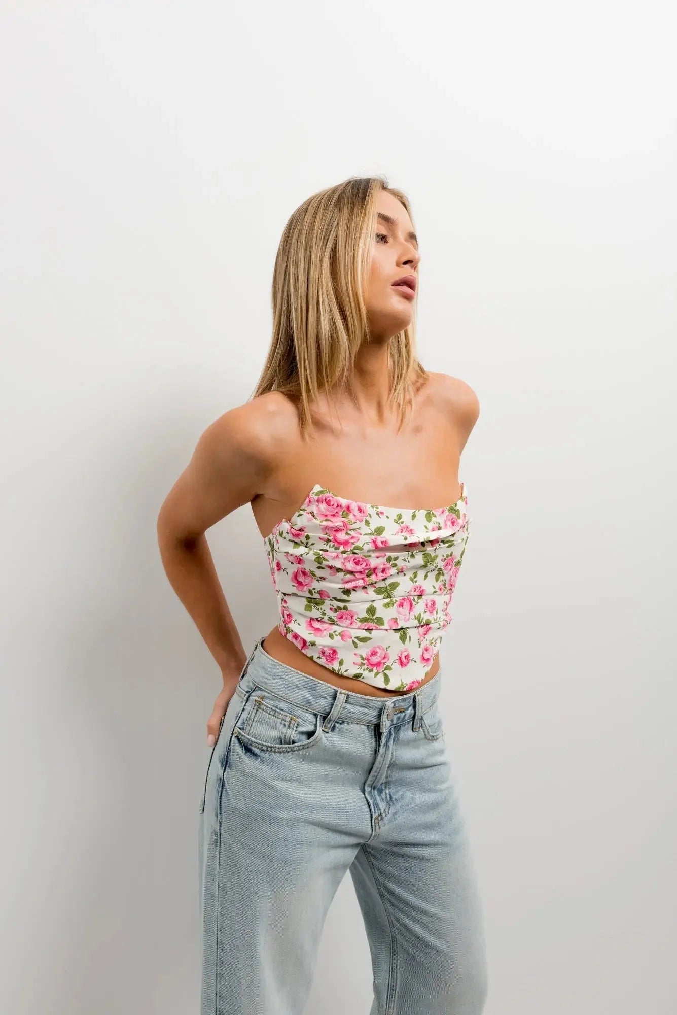 Femme portant une inspiration corset florale à roses, crop top blanc et jeans larges