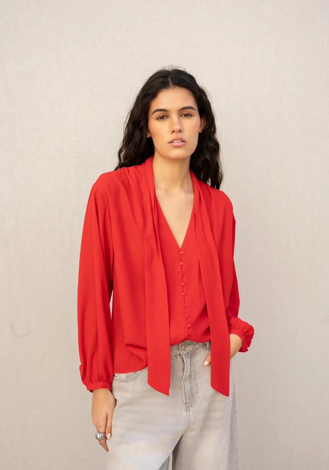 Une blouse rouge à manches longues pour femme avec un col en V et une fermeture à nouer à l'avant.