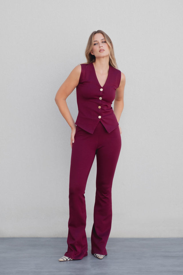 Modèle portant un débardeur tricot femme bordeaux à boutons dorés, assorti avec un pantalon pour un look chic.