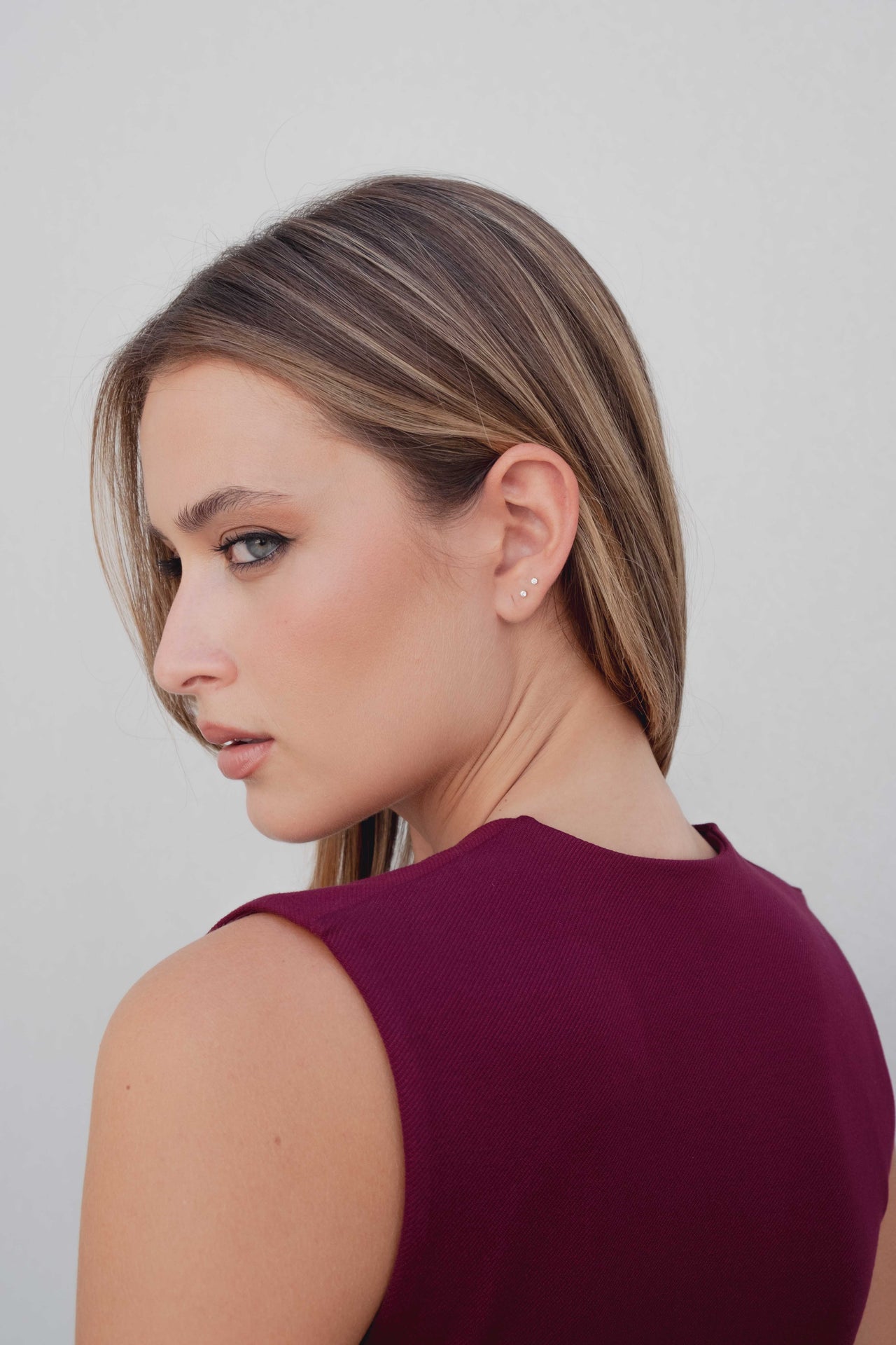 Vue arrière d'un modèle avec le débardeur tricot femme bordeaux à boutons dorés, mettant en valeur le design.