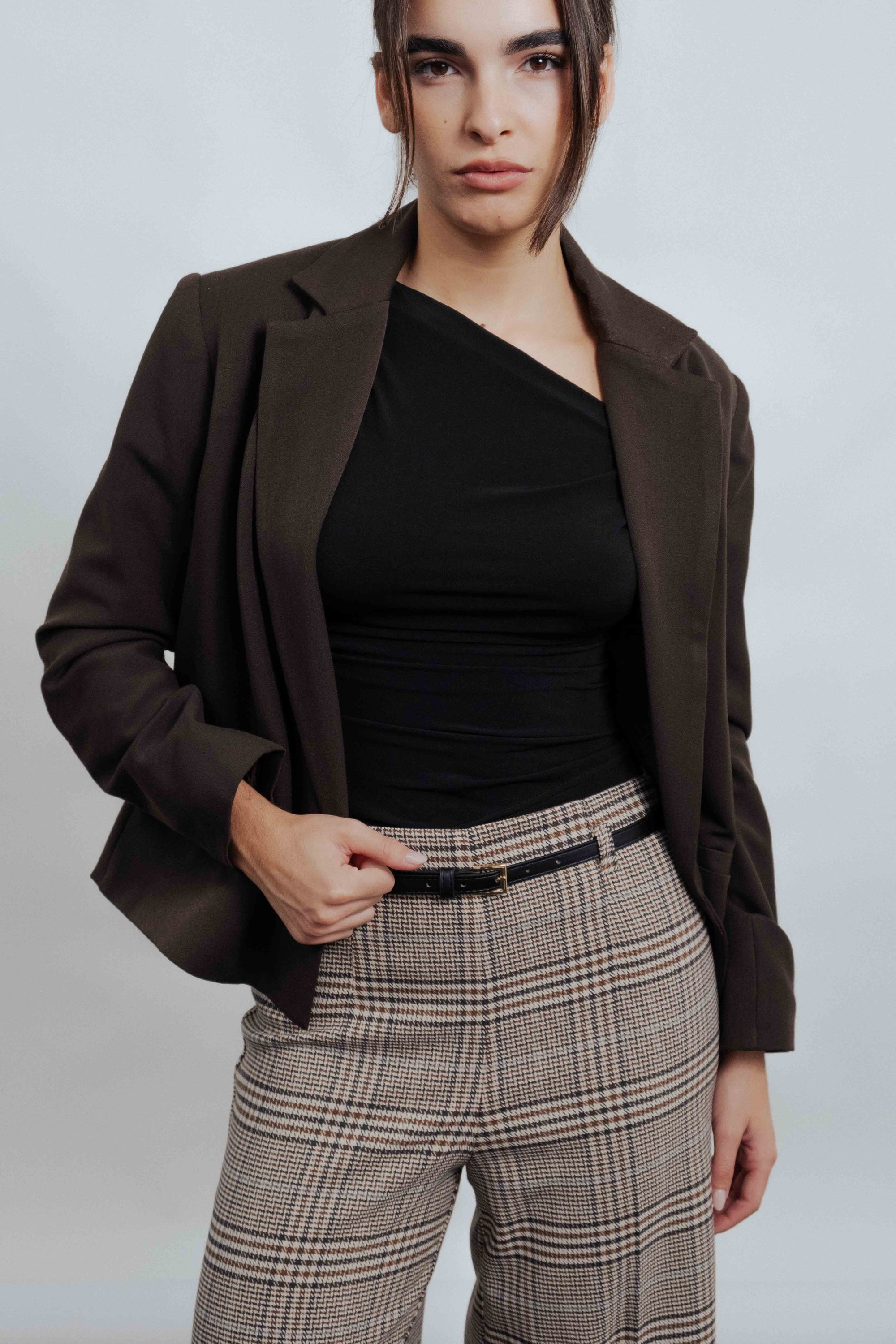 Gros plan sur une femme en Pantalon culotte à carreaux marron, avec un blazer élégant, affichant un style contemporain.