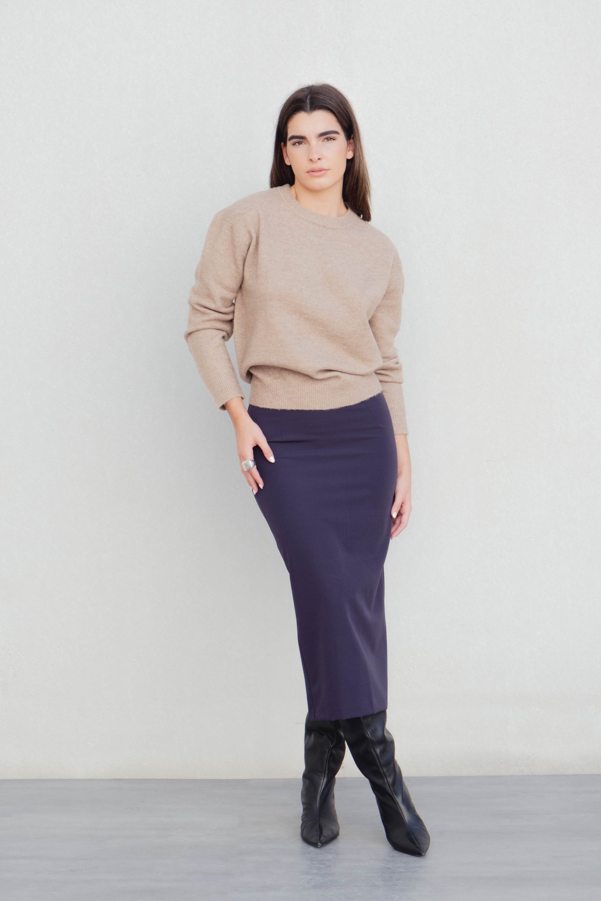 Femme affichant une jupe midi marine taille haute avec un pull beige, capturant le style décontracté de la jupe midi.