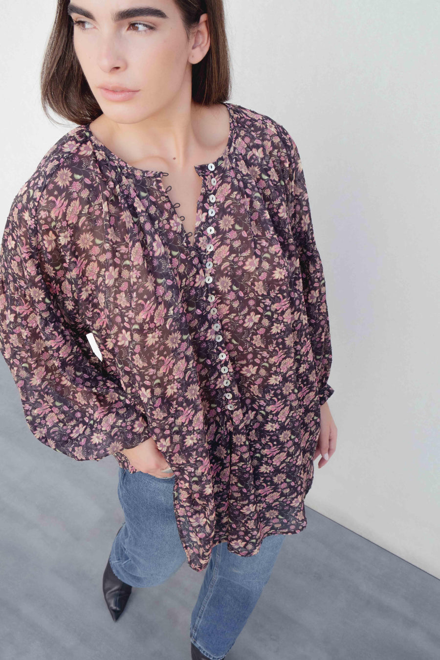 Vue aérienne d'une femme en blouse semi-transparente noire avec motifs floraux, mettant en valeur son élégance décontractée. Blouse fleurie femme.